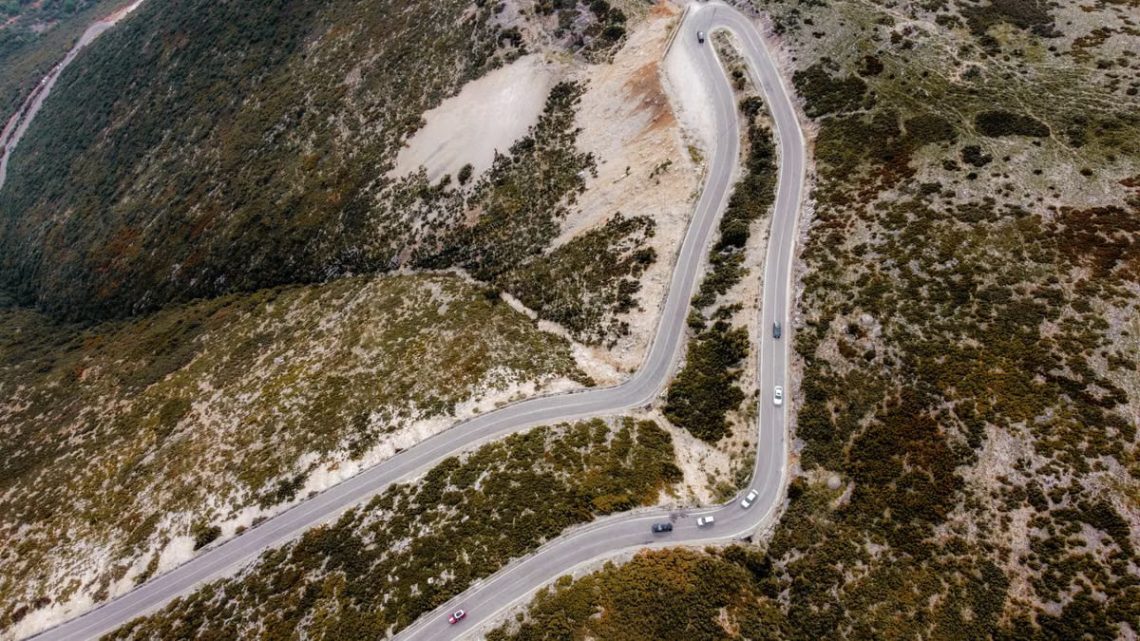 Captivating aerial shot of a winding road through autumn landscapes on a mountain.